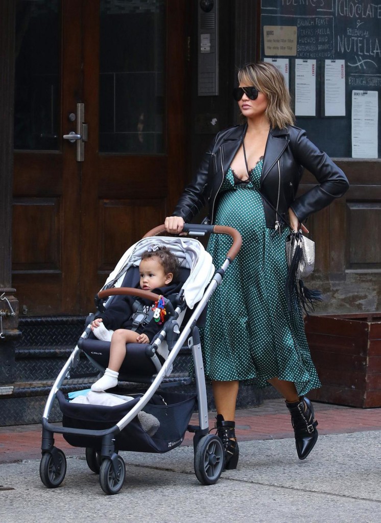 Pregnant Chrissy Teigen shows off her cleavage in a green and white polka dot dress as she takes daughter Luna for a walk in her stroller in Manhattan's Soho Neighborhood