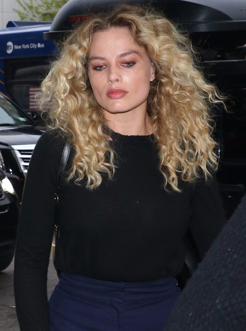 A curly haired Margot Robbie returns to her hotel in NYC