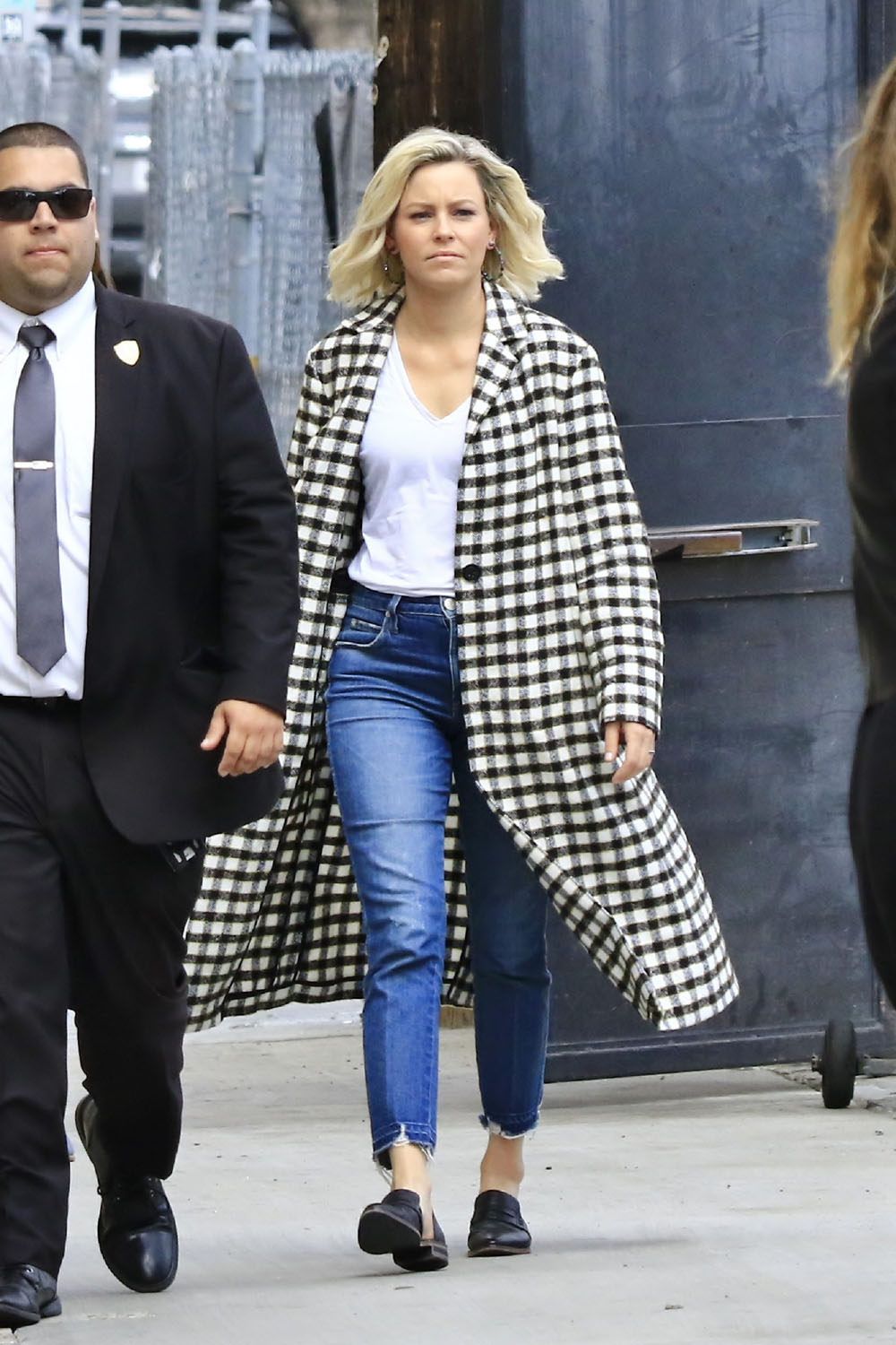 Elizabeth Banks arrives for an appearance on Jimmy Kimmel Live! wearing a long black and white checked coat
