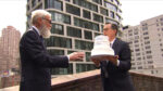 Colbert holding a cake next to Letterman. They're about to throw it off the roof