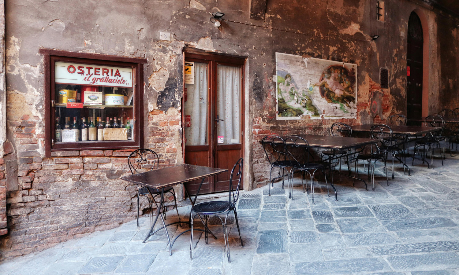 Vintage outdoor cafe setting with empty tables in historic Italian street.