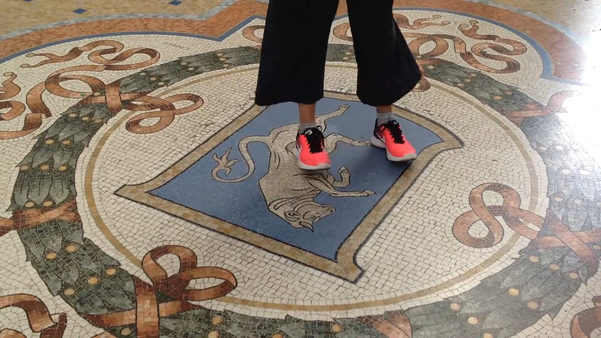 Close up view of person in orange shoes spinning on the bull mosaic