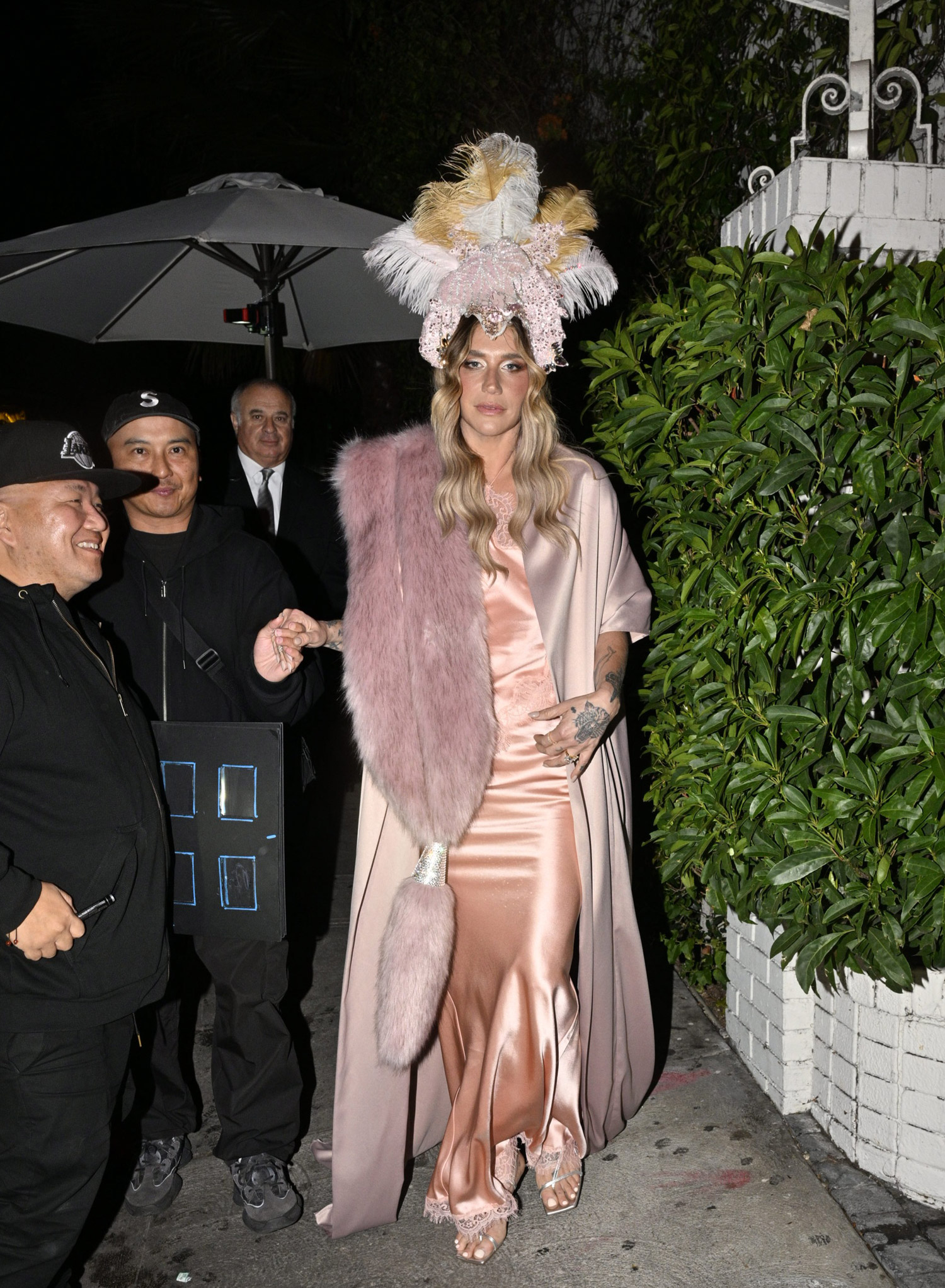 Kesha arrives for the Hollywood Reporter party at Chateau Marmont in Los Angeles, California, USA on 10 February 2026. She is in a pink silk slipdress with a satin robe-like overlay and has a giant feather headdress.