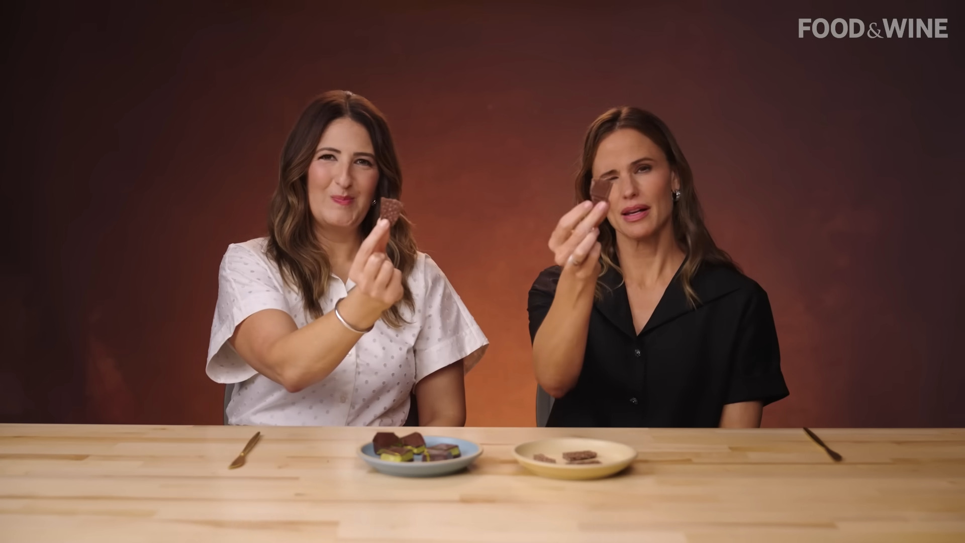 Screenshot of D'arcy Carden and Jennifer Garner holding up Nestle Crunch bar pieces