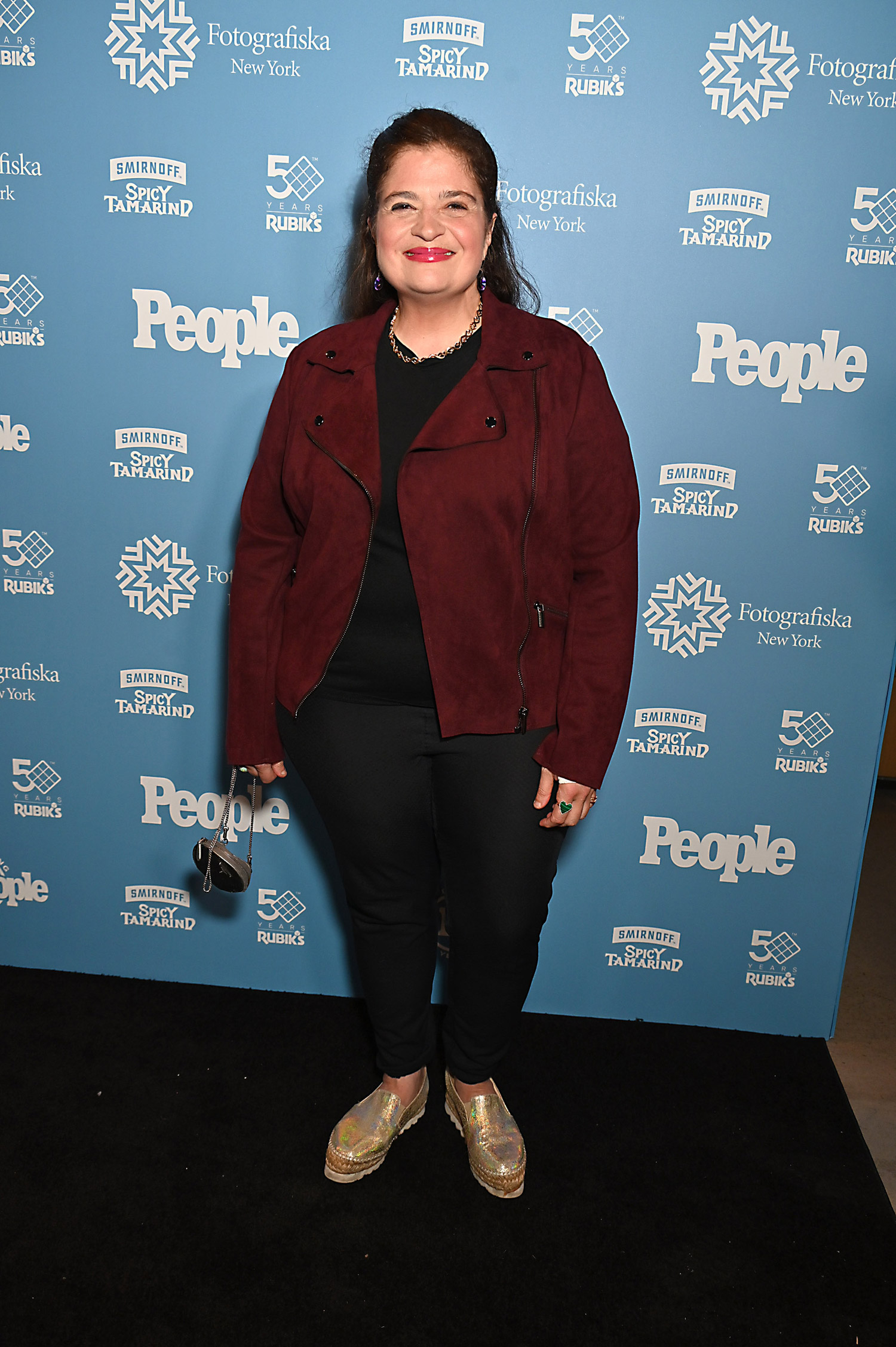 lex Guarnaschelli in a burgundy suede moto jacket, black pants and silver shoes at PEOPLE: Celebrating 50 Years exhibition opening at Fotografiska on 05/09/2024
