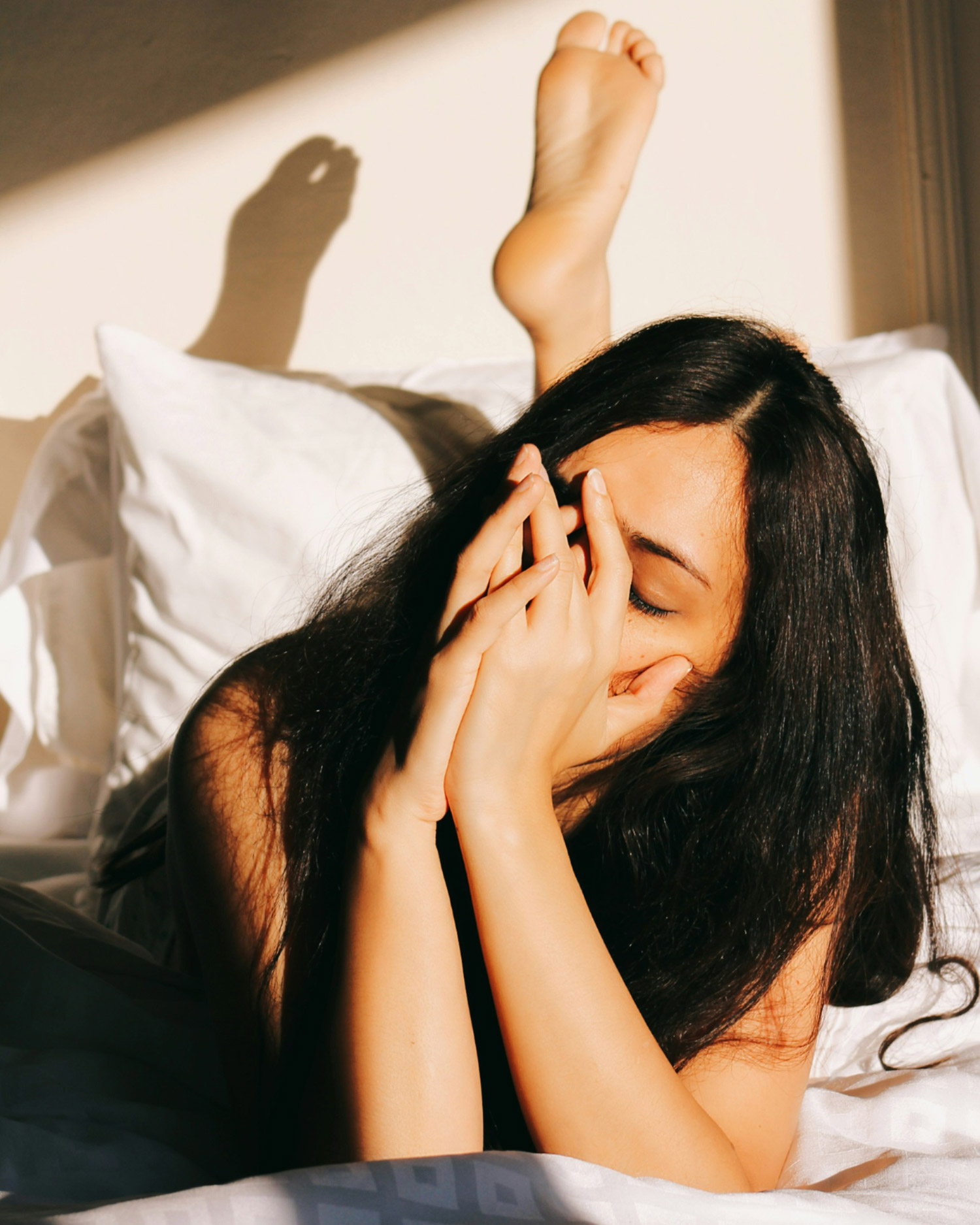 woman in bed holding her hands to her face