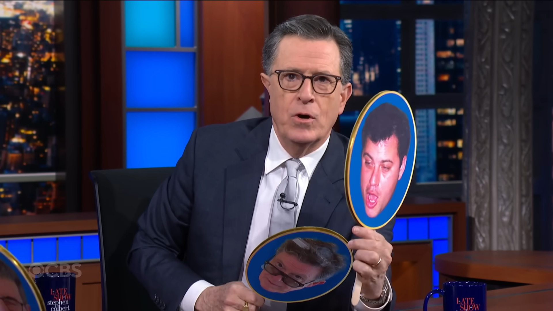 Colbert on his show holding up a photo of Kimmel