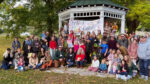 Crowd gathered in front of the gazebo in St. Croix, Minnesota with the banner 'Straightest Stick Contest 2026' behind them