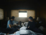 Elizabeth Holmes lying in bed with Nathan Fielder and Billy Evans on either side of her