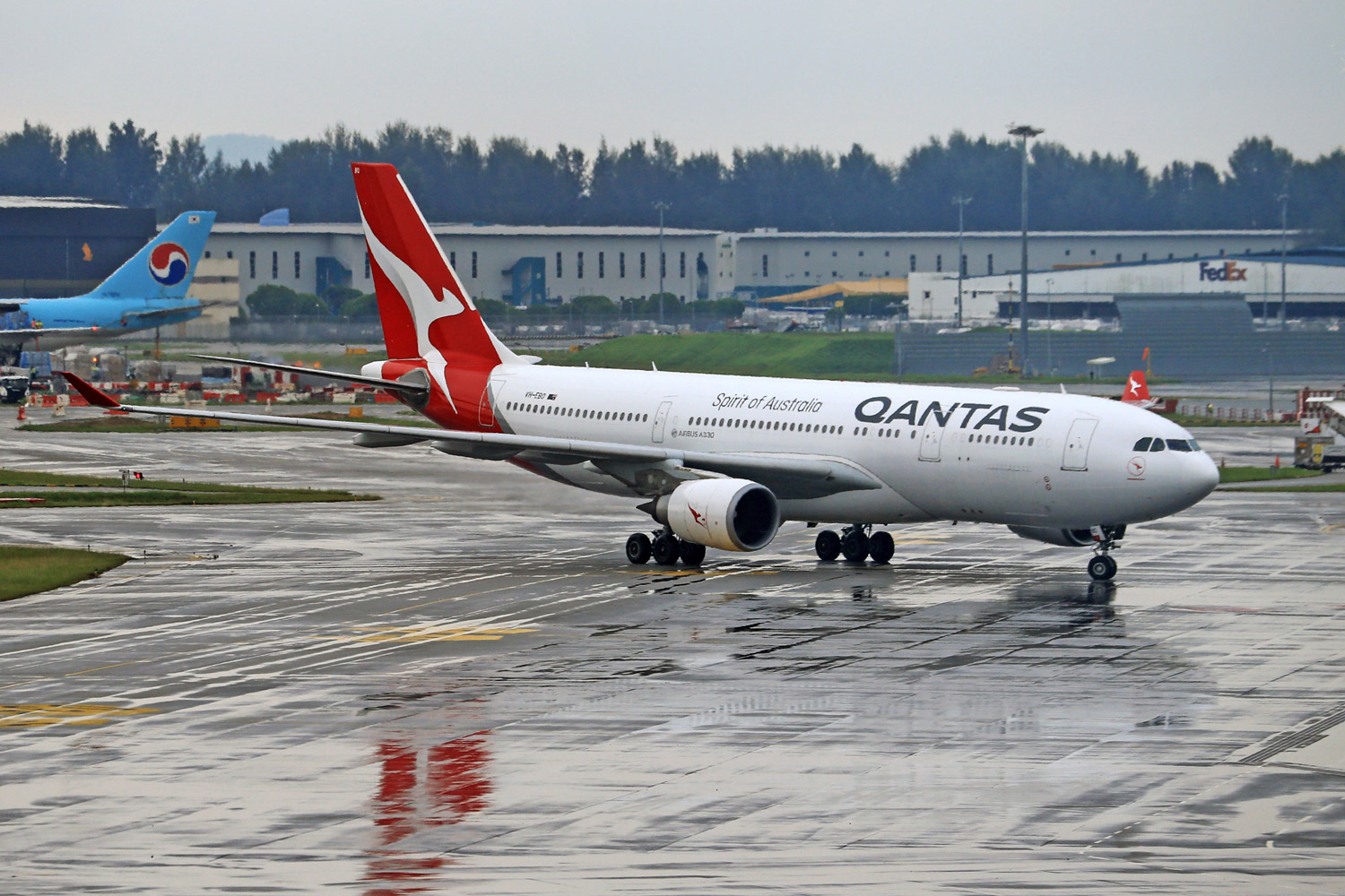 Qantas Airbus A330 taxiing on a rainy airport runway.