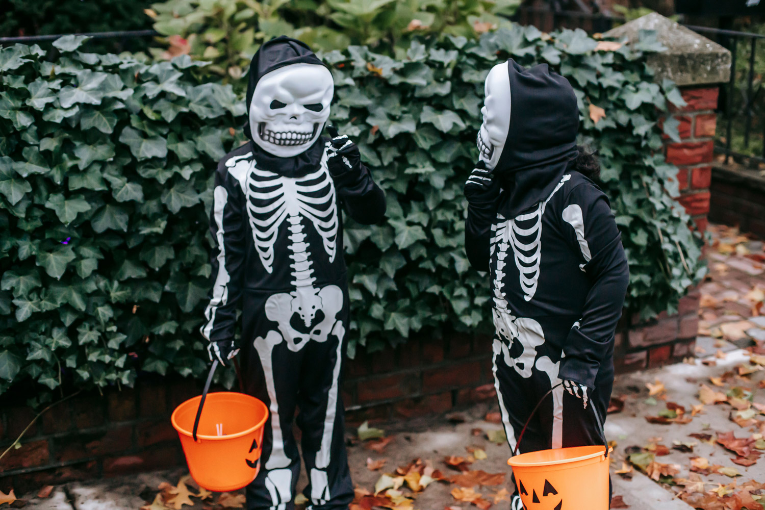Children in skeleton costumes trick or treating with their masks on