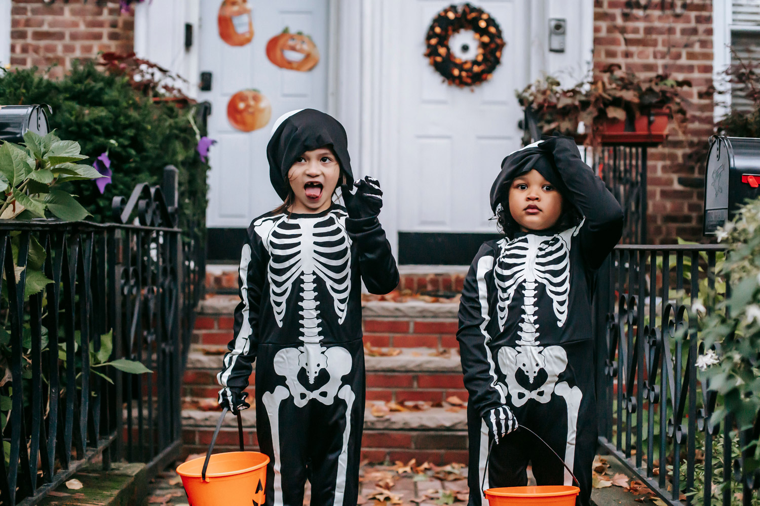 Children in skeleton costumes trick or treating with their masks pulled up